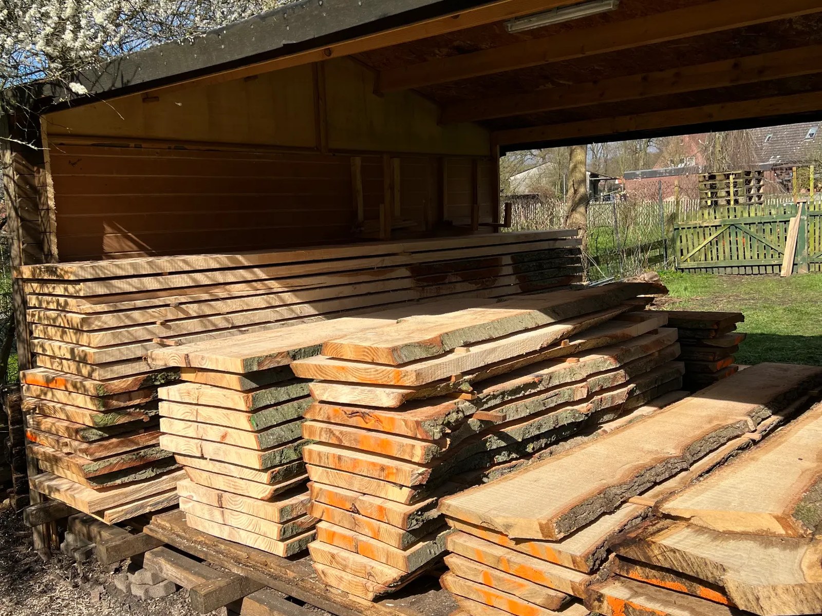 Gestapelte Bohlen und Bretter unter dem Holzlager von NF Möbeldesign